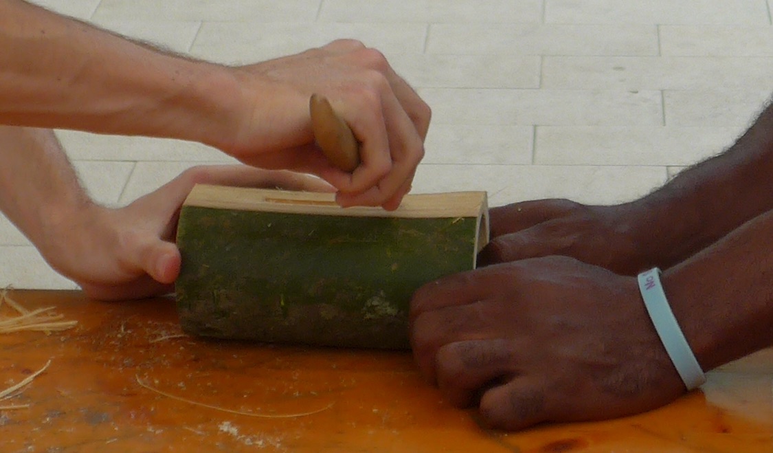 Drei Hände arbeiten an einem Bambus-Werkstück.